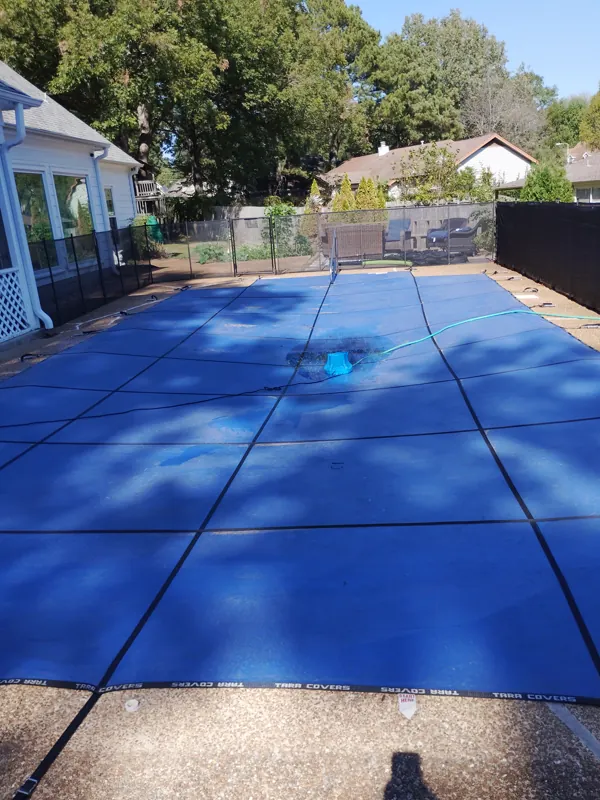 Blue mesh safety cover anchored over an inground pool