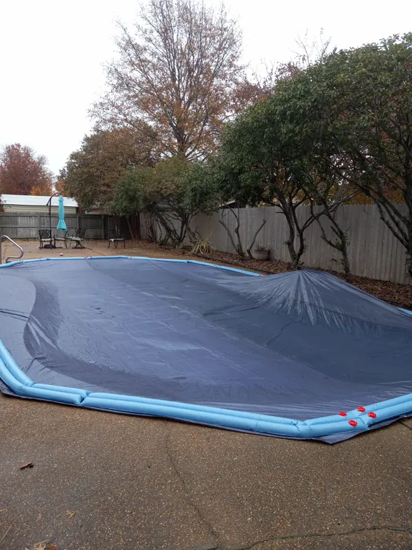 Freeform pool closed under a solid winter cover in the fall